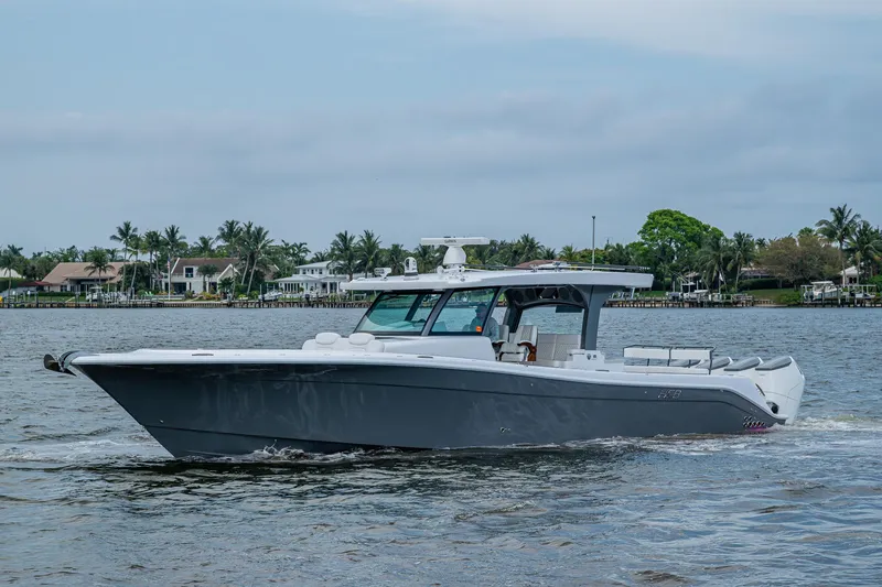 Slide: The Image of 2025 HCB 48 Campeon boat cruising on a calm waterway with scenic background. - 8