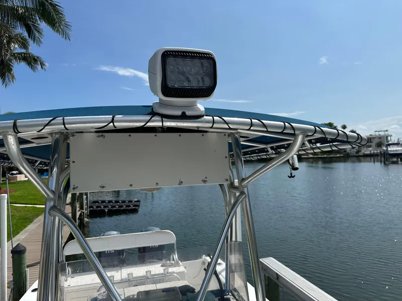 Slide: The Image of 2003 Cobia 254 Center Console boat with spotlight, docked by a serene waterfront. - 10