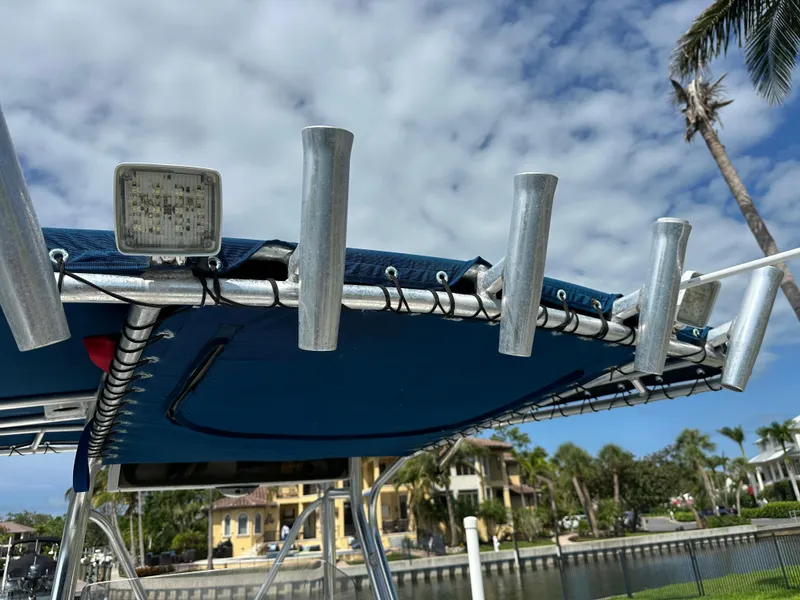 Slide: The Image of T-top of 2003 Cobia 254 Center Console boat with rod holders and light, under a cloudy sky. - 11