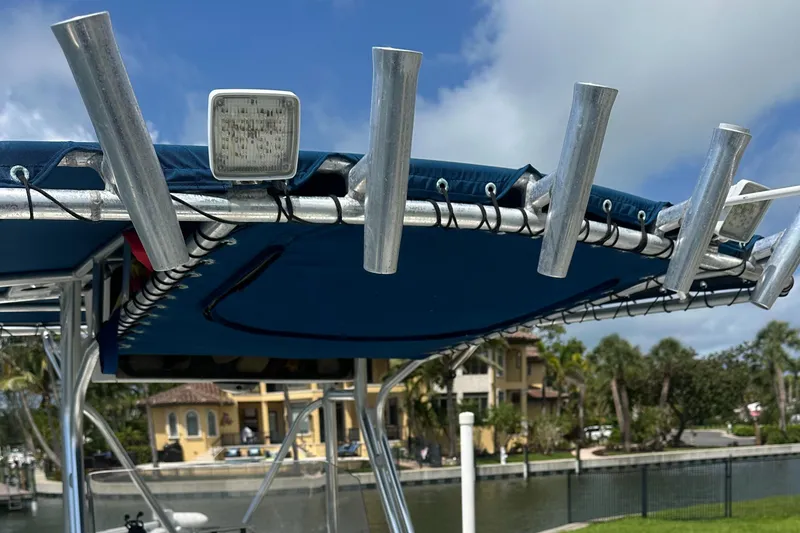 Slide: The Image of T-top rod holders on a 2003 Cobia 254 Center Console boat, docked by waterfront homes. - 14