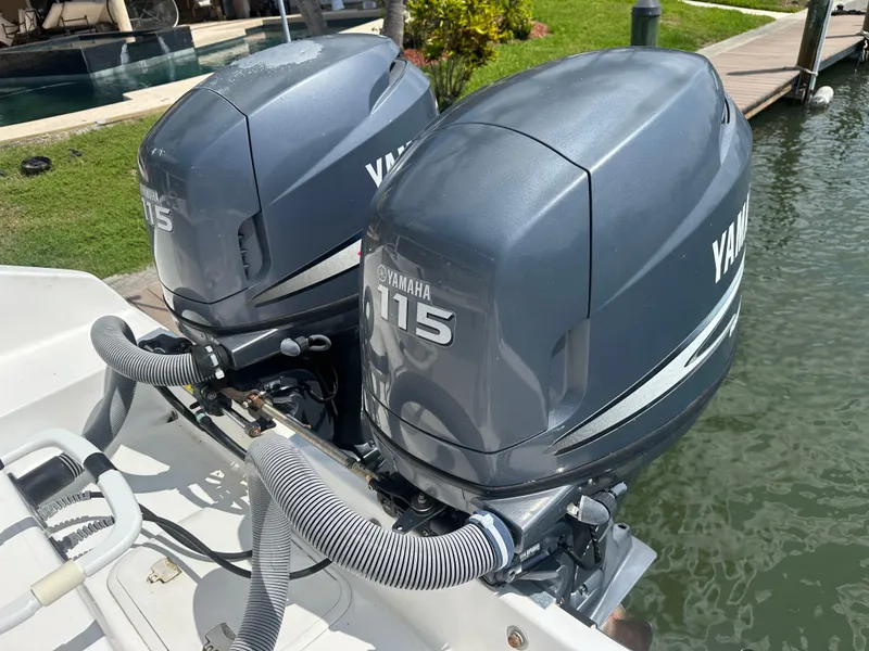 Slide: The Image of Twin Yamaha 115 engines on a 2003 Cobia 254 Center Console boat, docked by water. - 2