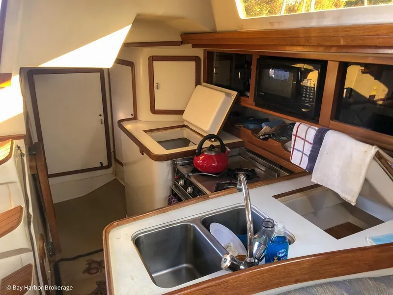 Slide: The Image of Interior of 1992 Catalina 42 sailboat kitchen with sink, stove, and red kettle. - 27