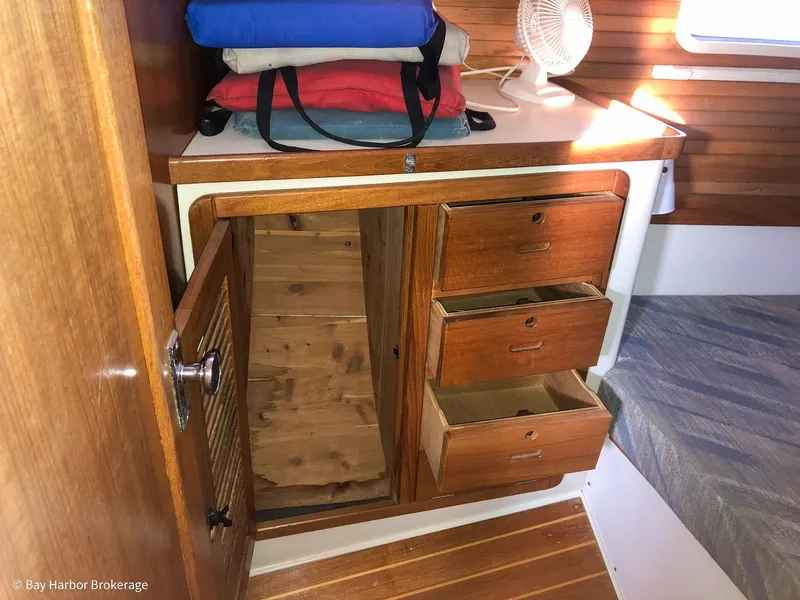 Slide: The Image of 1992 Catalina 42 interior with wooden cabinets, open drawers, and folded life jackets. - 37