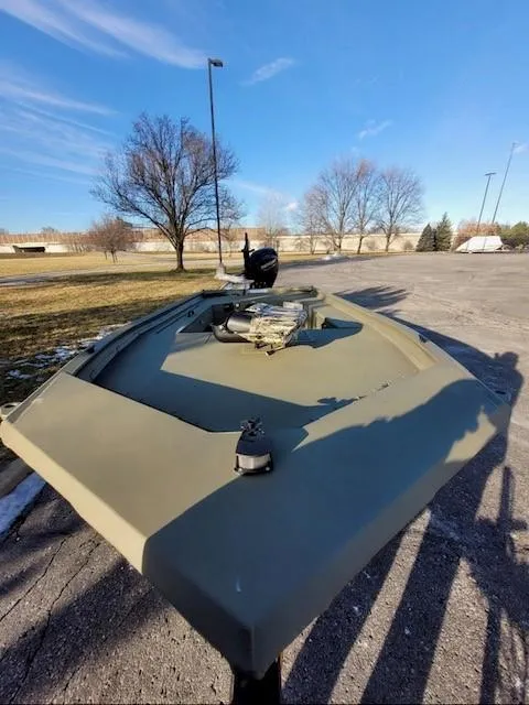 Slide: The Image of 2025 Tracker Grizzly 1654 T Sportsman boat in a parking lot under clear blue sky. - 2