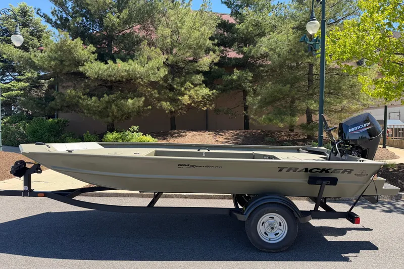 Slide: The Image of 2025 Tracker Grizzly 1654 T Sportsman boat on trailer, parked outdoors. - 2
