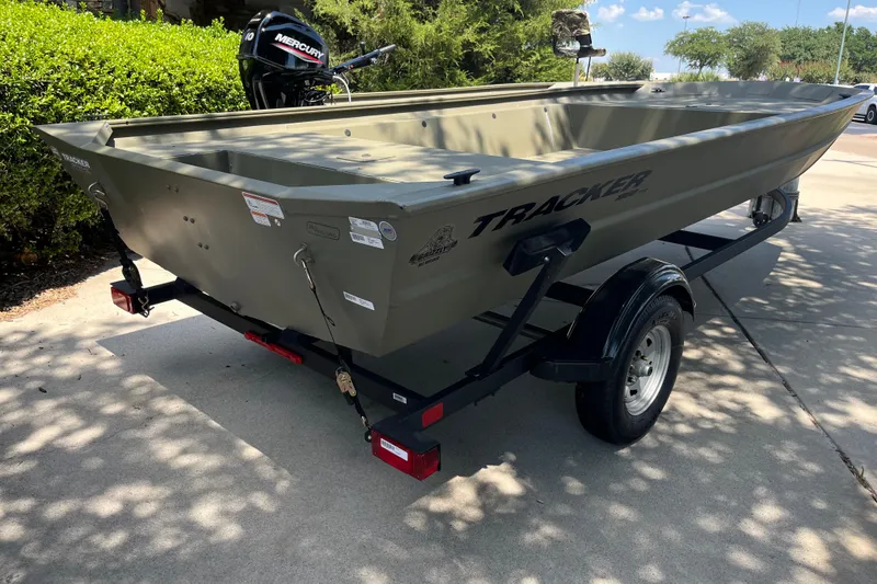 Slide: The Image of 2025 Tracker GRIZZLY 1860 Utility boat on trailer, parked outdoors. - 2