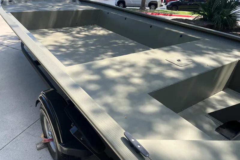 Slide: The Image of 2025 Tracker GRIZZLY 1860 Utility boat, olive green, parked on concrete driveway. - 3