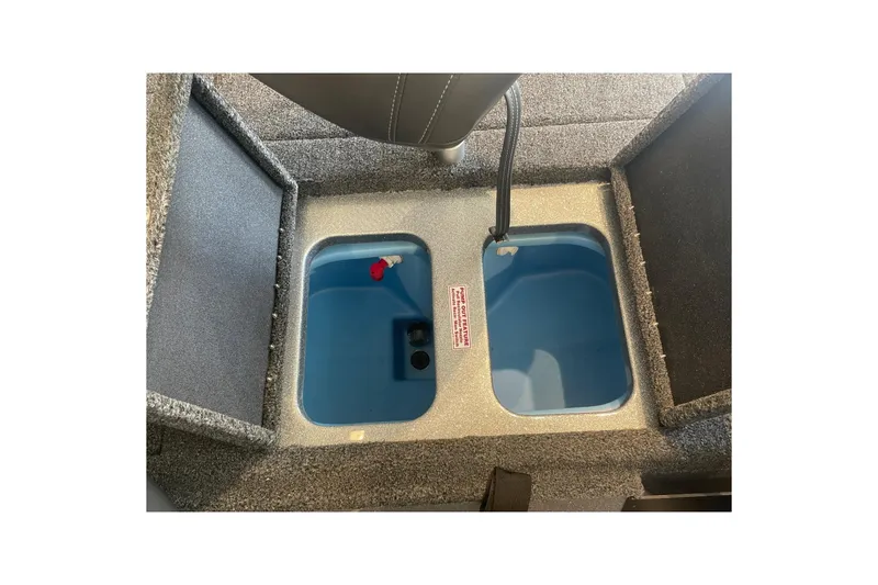 Slide: The Image of 2024 Nitro Z18 boat storage compartment with blue interior and gray carpeted edges. - 10