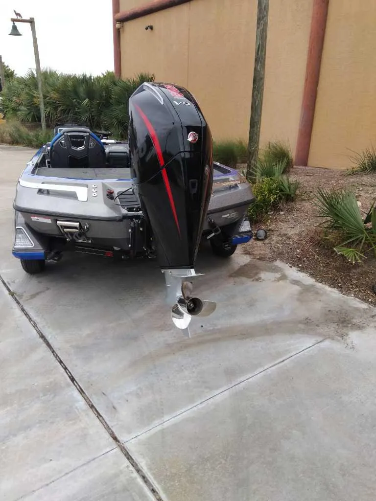 Slide: The Image of 2025 Ranger Z521R boat with powerful outboard motor, parked on concrete near greenery. - 6