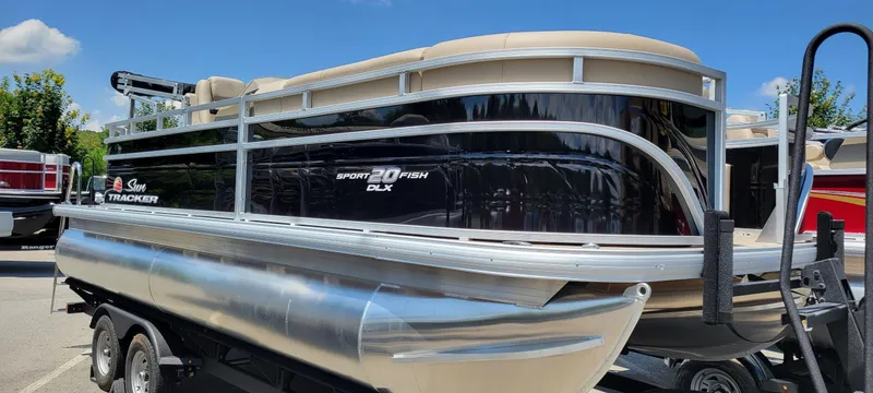 The Image of 2025 Sun Tracker SportFish 20 DLX pontoon boat on trailer, shiny black exterior, sunny day. - 0