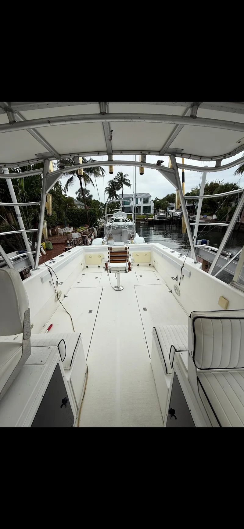 Slide: The Image of 2000 Powercat Catamaran deck view with seating, canopy, and waterfront backdrop. - 7