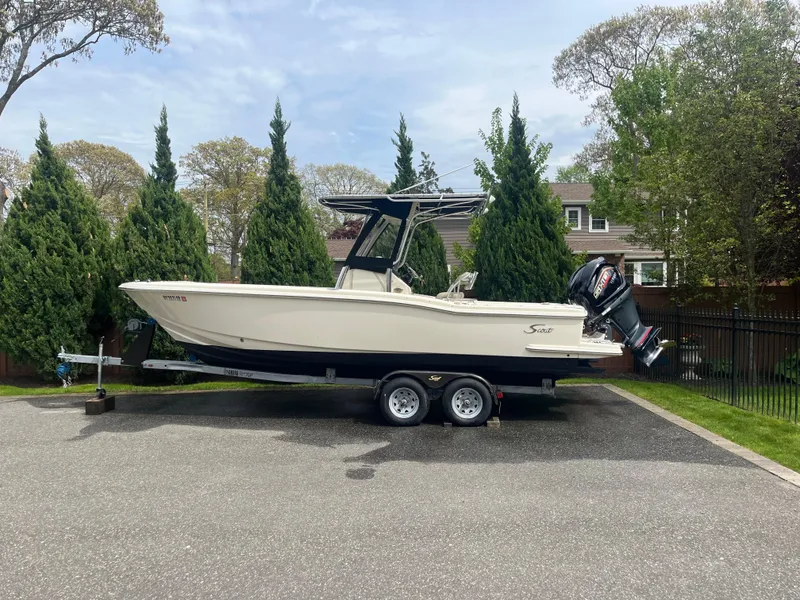 The Image of 2005 Scout 235 Sportfish boat on trailer, parked outdoors near trees. - 1