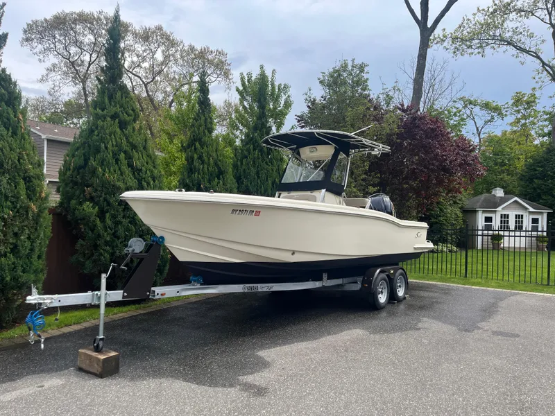 Slide: The Image of 2005 Scout 235 Sportfish boat on trailer, parked in driveway with trees in background. - 4