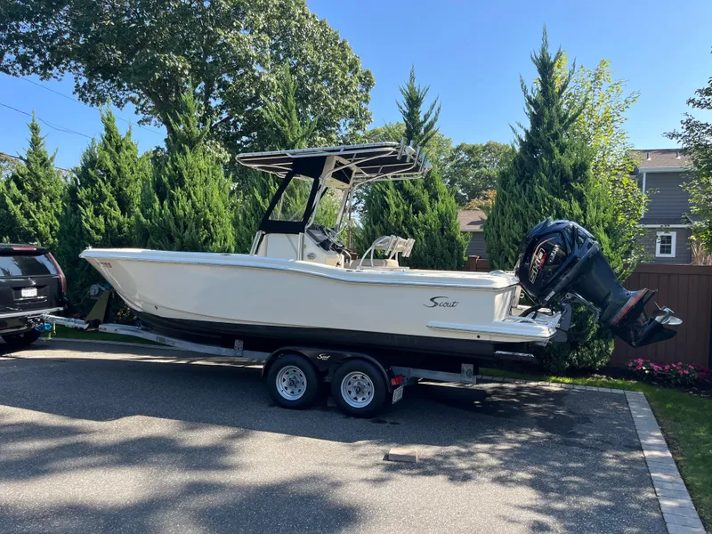 Slide: The Image of 2005 Scout 235 Sportfish boat on trailer, parked outdoors with trees in the background. - 9