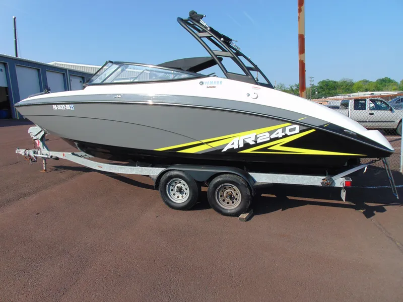 The Image of 2020 Yamaha AR240 boat on trailer, gray and white with yellow accents, parked outdoors. - 1