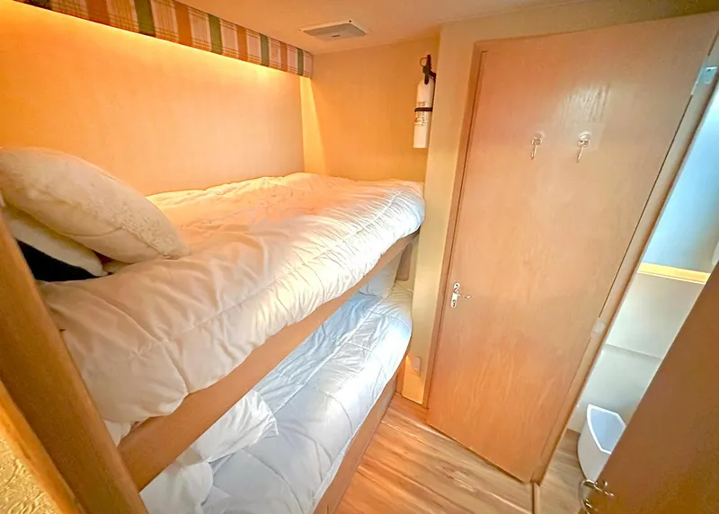 Slide: The Image of 1994 Hatteras Cockpit Motoryacht cabin with bunk beds and wooden interior. - 26