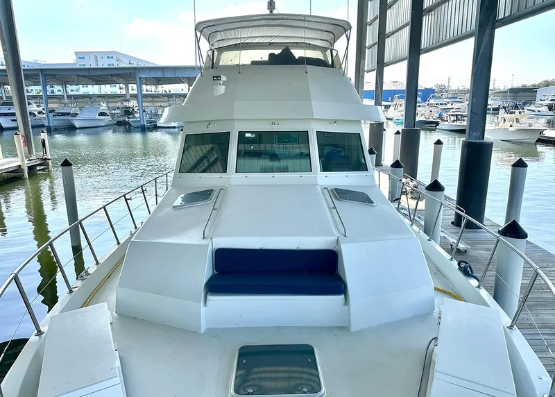 Slide: The Image of 1994 Hatteras Cockpit Motoryacht docked in a marina, showcasing sleek design and spacious deck. - 3