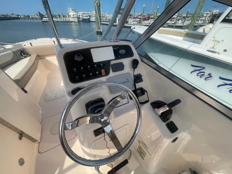 Slide: The Image of 2014 Grady-White Freedom 255 boat helm with steering wheel and control panel, docked at marina. - 18