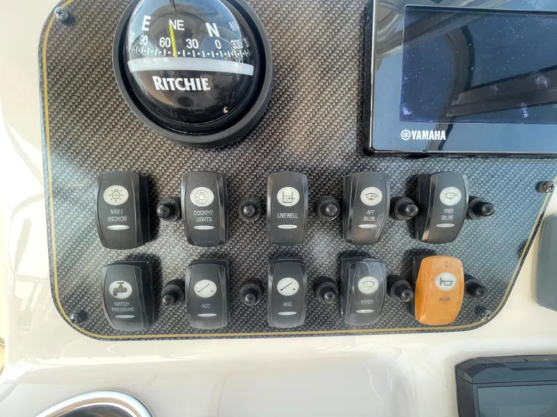 Slide: The Image of Control panel of 2014 Grady-White Freedom 255 boat with switches and compass. - 24