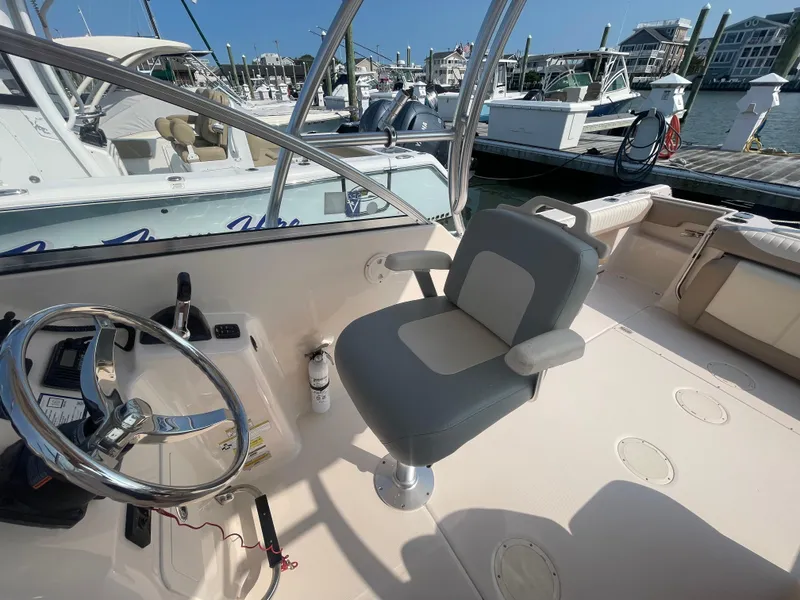 Slide: The Image of 2014 Grady-White Freedom 255 boat interior with steering wheel and seating at marina. - 29