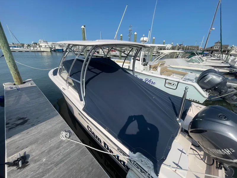 Slide: The Image of 2014 Grady-White Freedom 255 boat docked at marina, covered with navy blue tarp. - 49