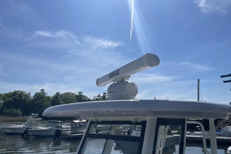 Slide: The Image of 2023 Robalo R270 Center Console with Simrad radar, docked under clear blue sky. - 22
