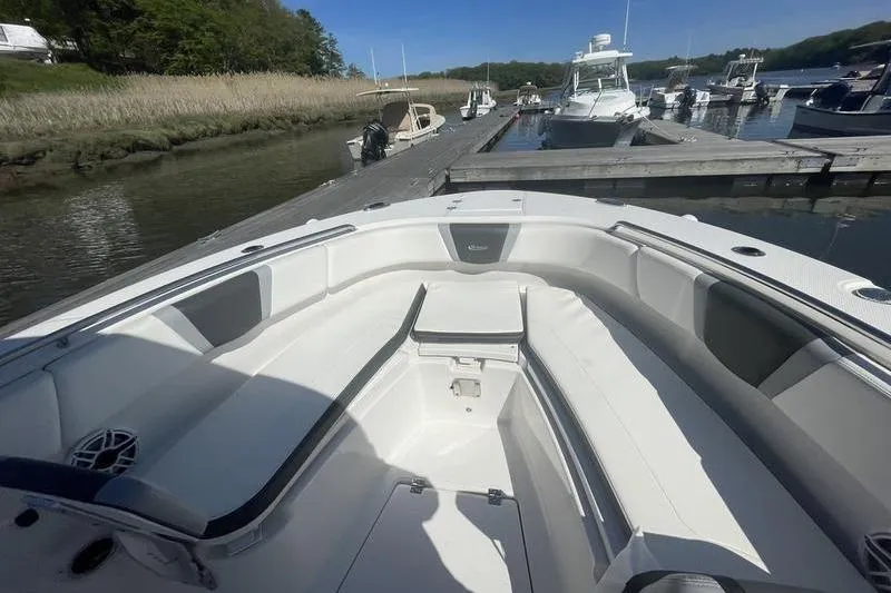 Slide: The Image of 2023 Robalo R270 Center Console boat docked at a marina, featuring spacious seating. - 23