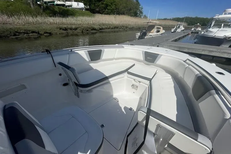 Slide: The Image of 2023 Robalo R270 Center Console boat interior with seating, docked by a serene riverside. - 24