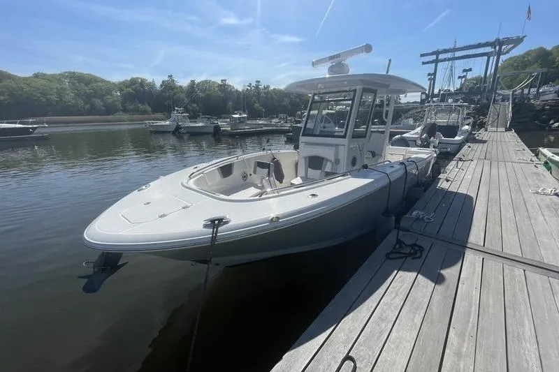 Slide: The Image of 2023 Robalo R270 Center Console boat docked at a marina under clear skies. - 6