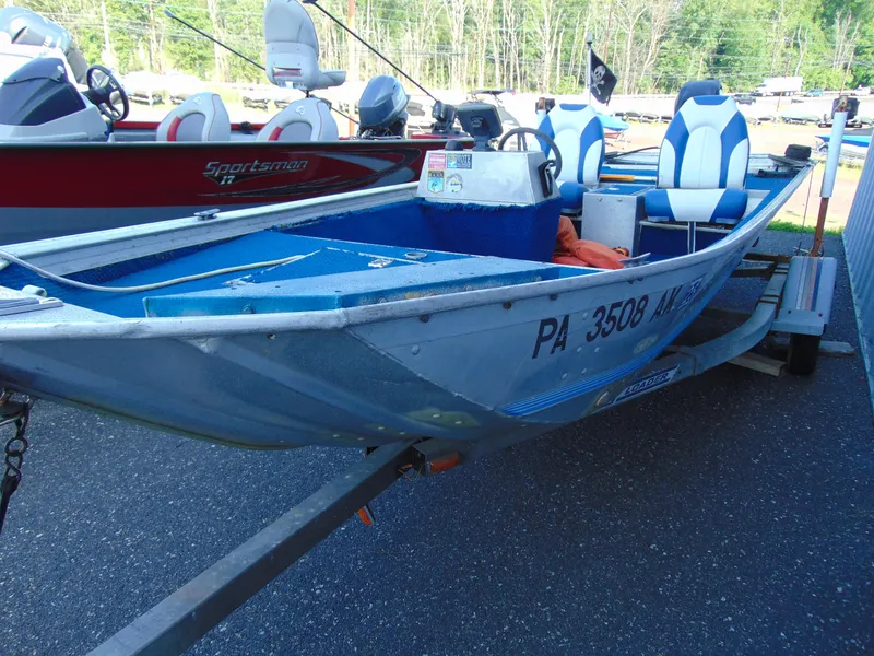 Slide: The Image of 1985 Fisher Hawk 3V boat on trailer, blue and white, parked outdoors. - 9