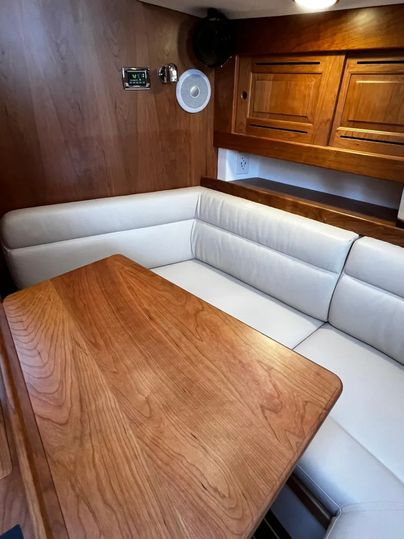 Slide: The Image of 2025 Tartan 395 yacht interior with wooden table and white cushioned seating. - 14