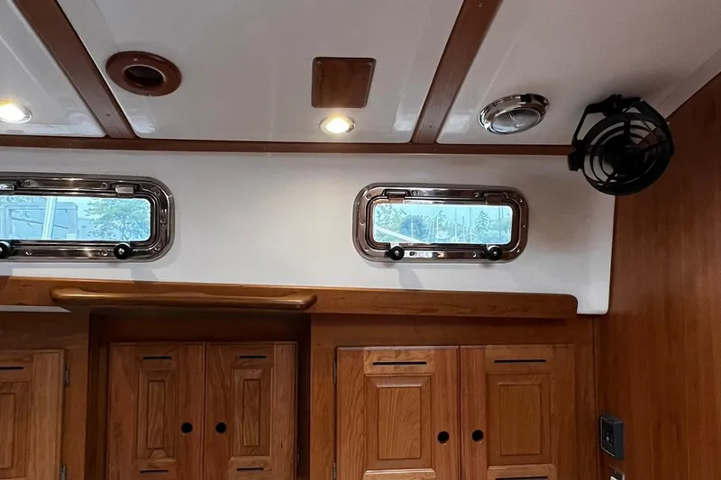 Slide: The Image of Interior of 2025 Tartan 395 yacht with wooden cabinets and porthole windows. - 26