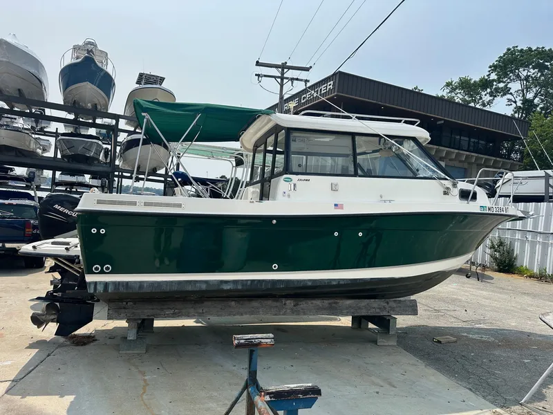 The Image of 2004 Trophy 2359 Hardtop boat on trailer, parked outdoors under clear blue sky. - 0