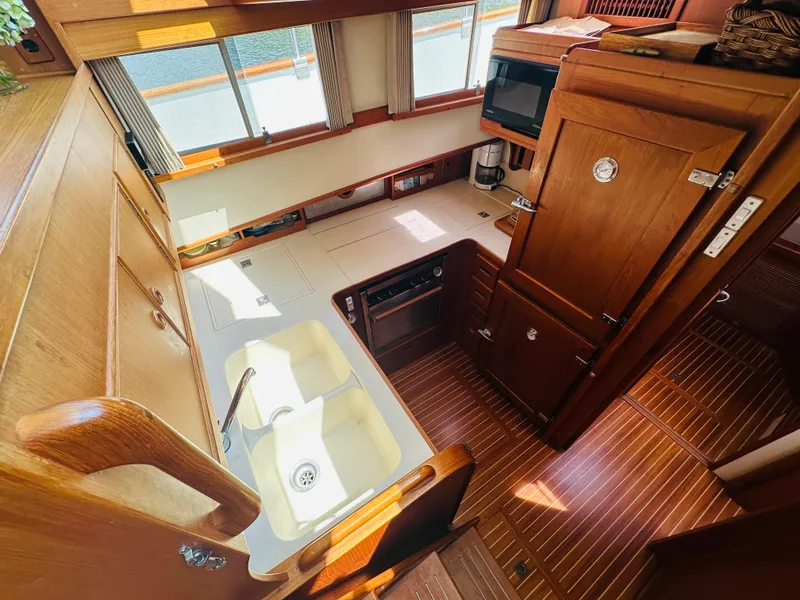 Slide: The Image of 1998 Grand Banks 49 Classic yacht kitchen with wooden cabinetry and dual sink. - 36