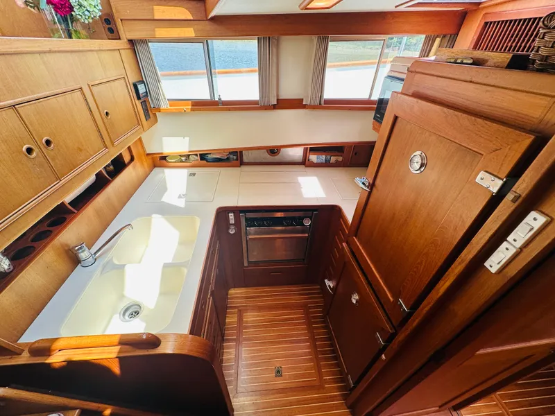 Slide: The Image of Interior of 1998 Grand Banks 49 Classic yacht, featuring a wooden kitchen with sink and appliances. - 37