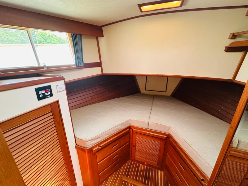 Slide: The Image of 1998 Grand Banks 49 Classic cabin interior with wood finish and cozy bedding. - 48