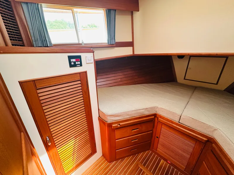 Slide: The Image of 1998 Grand Banks 49 Classic cabin interior with wooden finish and cozy bed. - 49