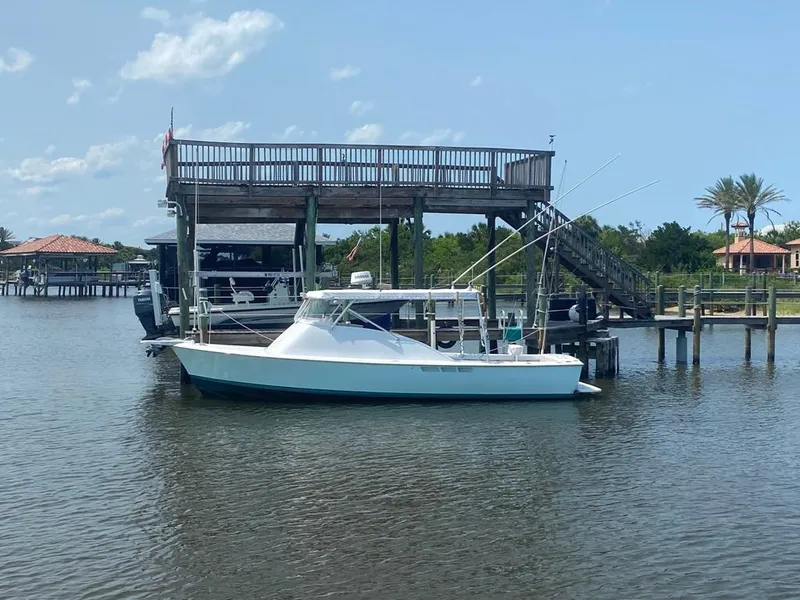 Slide: The Image of 1970 Bertram 31 Bahia Mar boat docked near a wooden structure on a sunny day. - 2