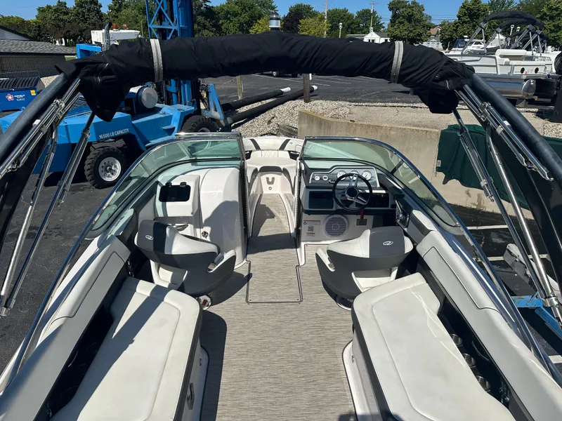 Slide: The Image of 2018 Regal 2500 Bowrider boat interior with seating and steering wheel, docked outdoors. - 2