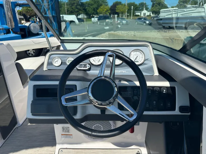 Slide: The Image of 2018 Regal 2500 Bowrider dashboard with steering wheel and gauges in a marina setting. - 4
