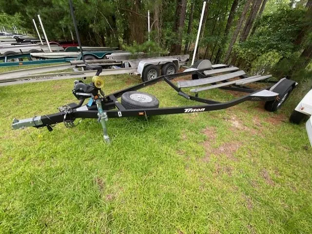 Slide: The Image of 2016 Triton 179 TrX boat trailer on grass, surrounded by trees and other trailers. - 12