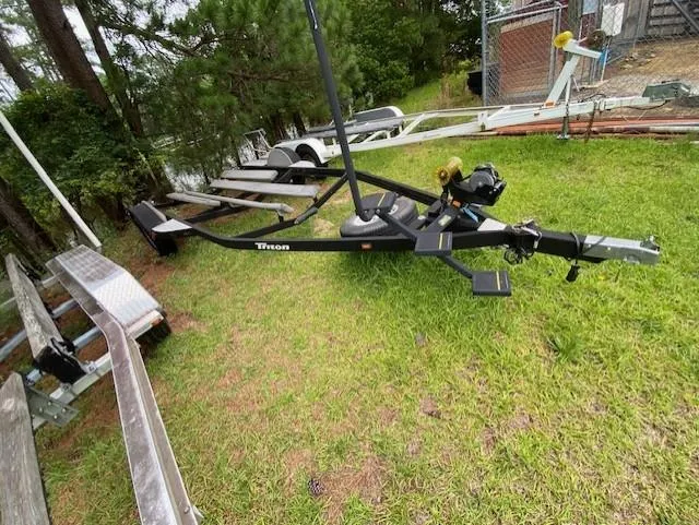 Slide: The Image of 2016 Triton 179 TrX boat trailer on grass, surrounded by trees and fencing. - 13