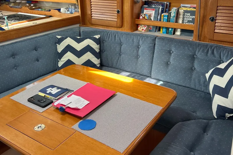 Slide: The Image of Cozy Catalina 36MKII 1998 yacht interior with blue cushions, wooden table, and nautical decor. - 31