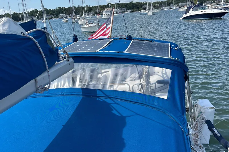 Slide: The Image of Catalina 36MKII sailboat with blue cover and solar panels, docked in a marina, 1998 model. - 7