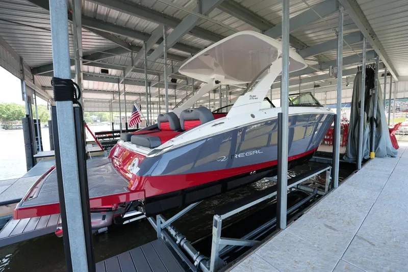 Slide: The Image of 2025 Regal LS9 boat docked in a covered marina, featuring sleek red and white design. - 19