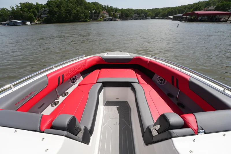 Slide: The Image of 2025 Regal LS9 boat interior with red and gray seating on a calm lake. - 36
