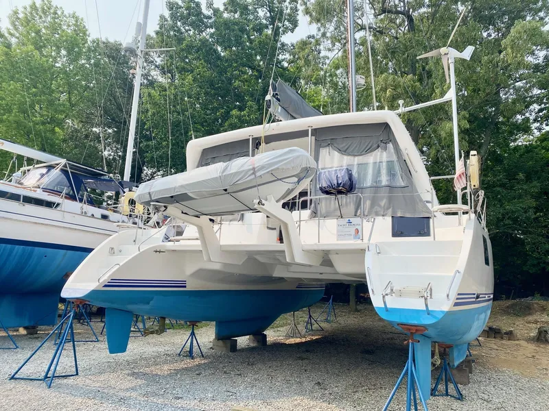 Slide: The Image of 2016 Celtic Yachts 40 catamaran on stands, surrounded by trees and other boats. - 2