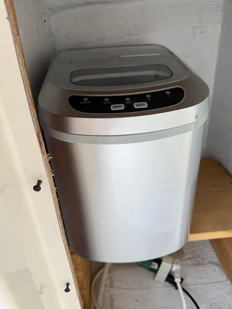 Slide: The Image of Compact silver ice maker on a wooden shelf in a Maxum 3700 SCR boat. - 11