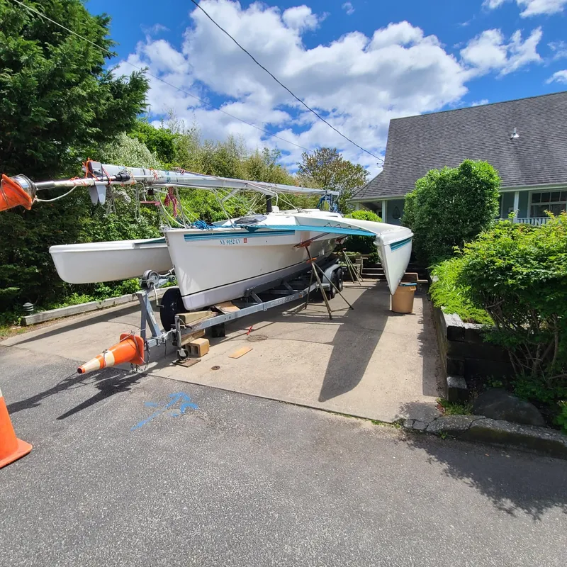 The Image of 1992 Corsair F-27 trimaran on trailer in driveway, surrounded by greenery and a house. - 1