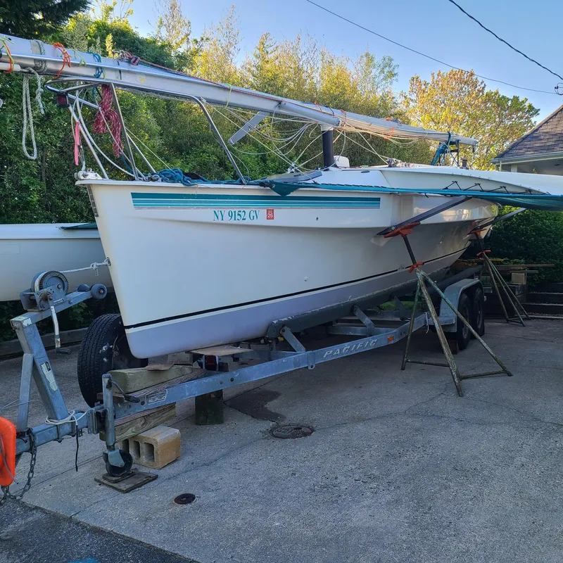 Slide: The Image of 1992 Corsair F-27 sailboat on trailer, parked outdoors, surrounded by greenery. - 2